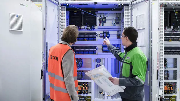 An automation manager and field technician inspect I/O and controllers of a distributed control system (DCS)